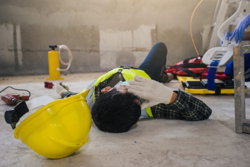 construction worker lying on ground holding head
