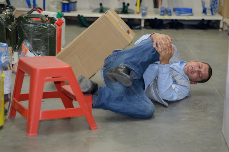 warehouse worker clutching knee after fall