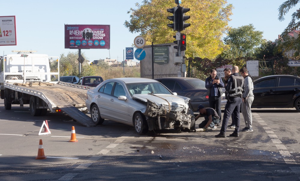 Car accident, head-on collision. A tow truck loads a wrecked car after an accident. Traffic police officer during an investigation in a traffic accident zone